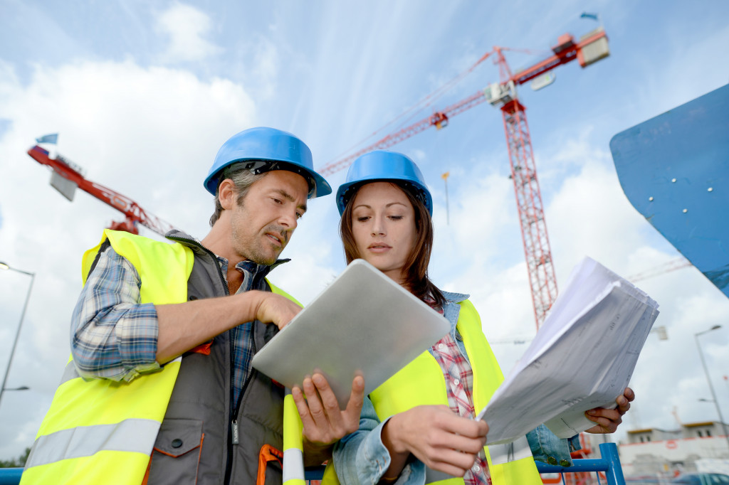 Two people talking while looking at a tablet on a construction site