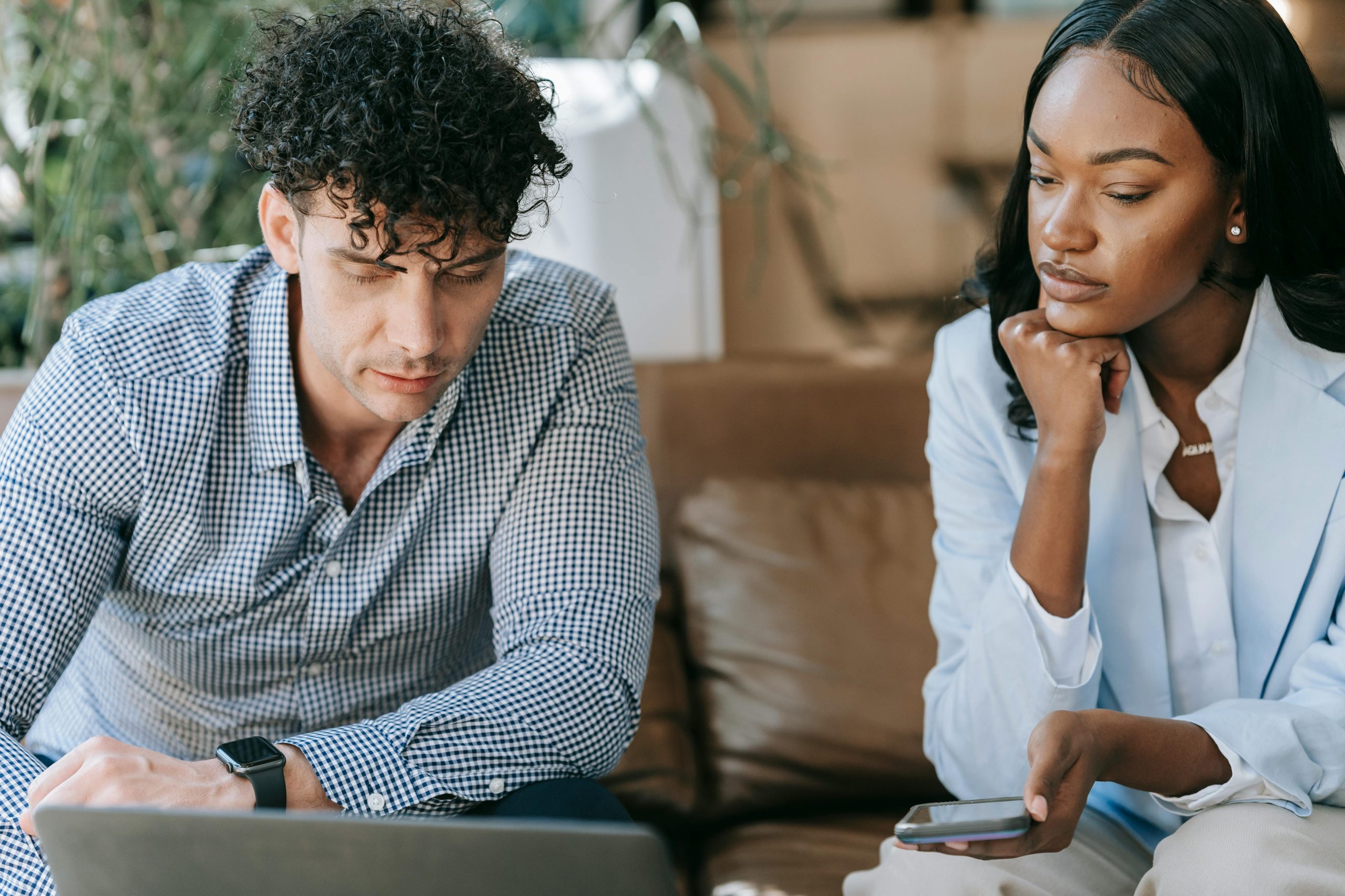 professionally dressed man showing something on his laptop to a woman in a blazer